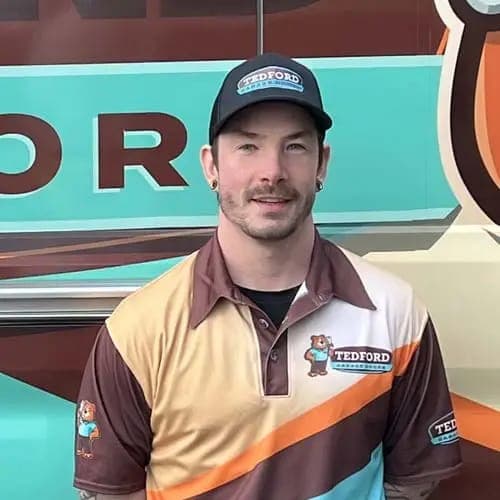 A smiling Tedford technician in a Tedford uniform and cap