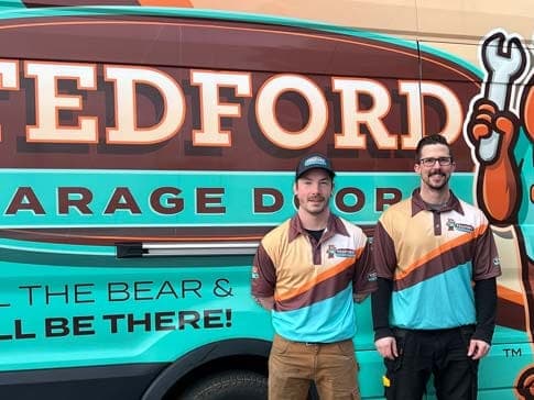 Two Tedford technicians standing beside a Tedford service van painted with the bear mascot
